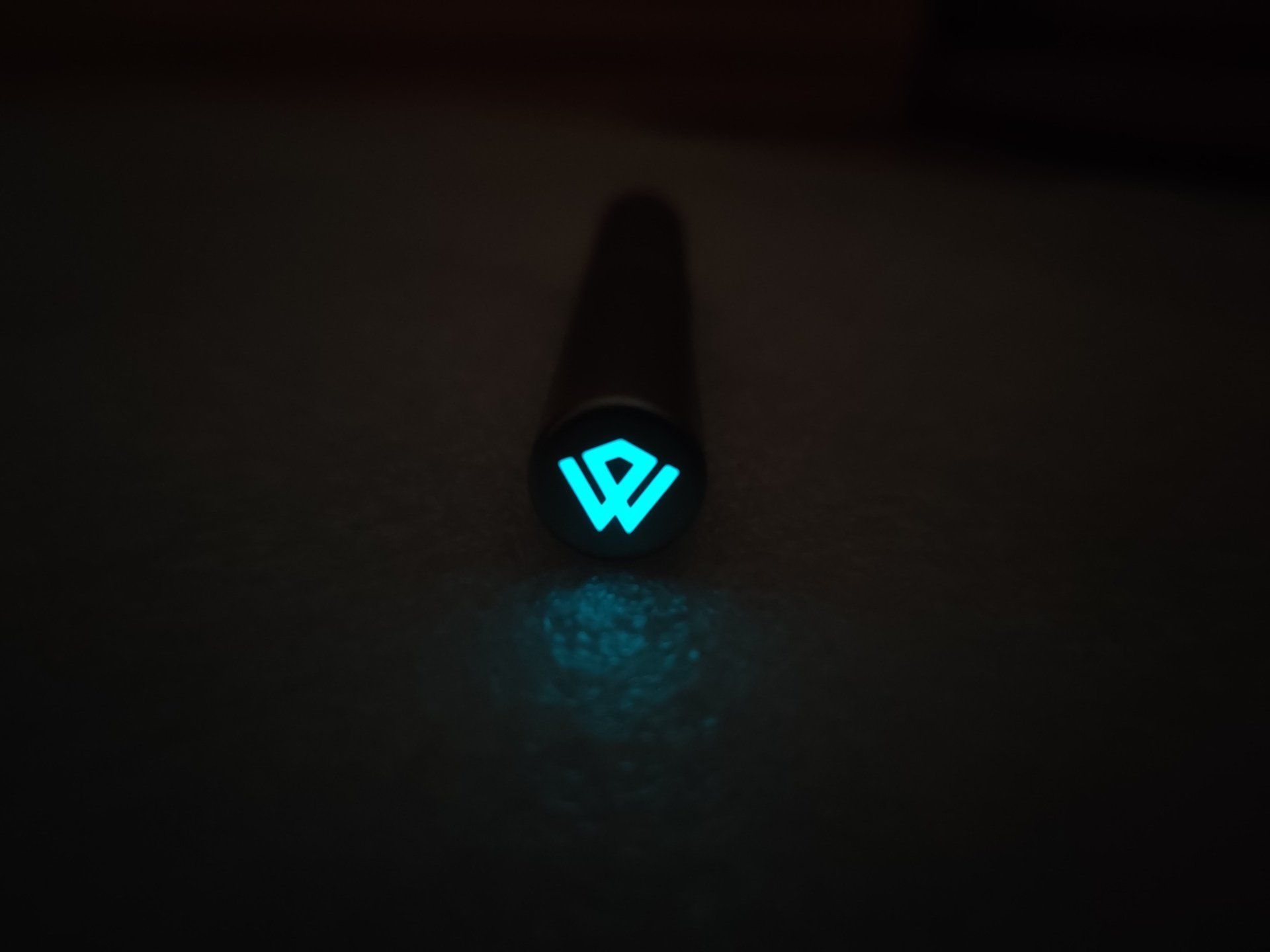 A blue light is shining on a black object in the dark.