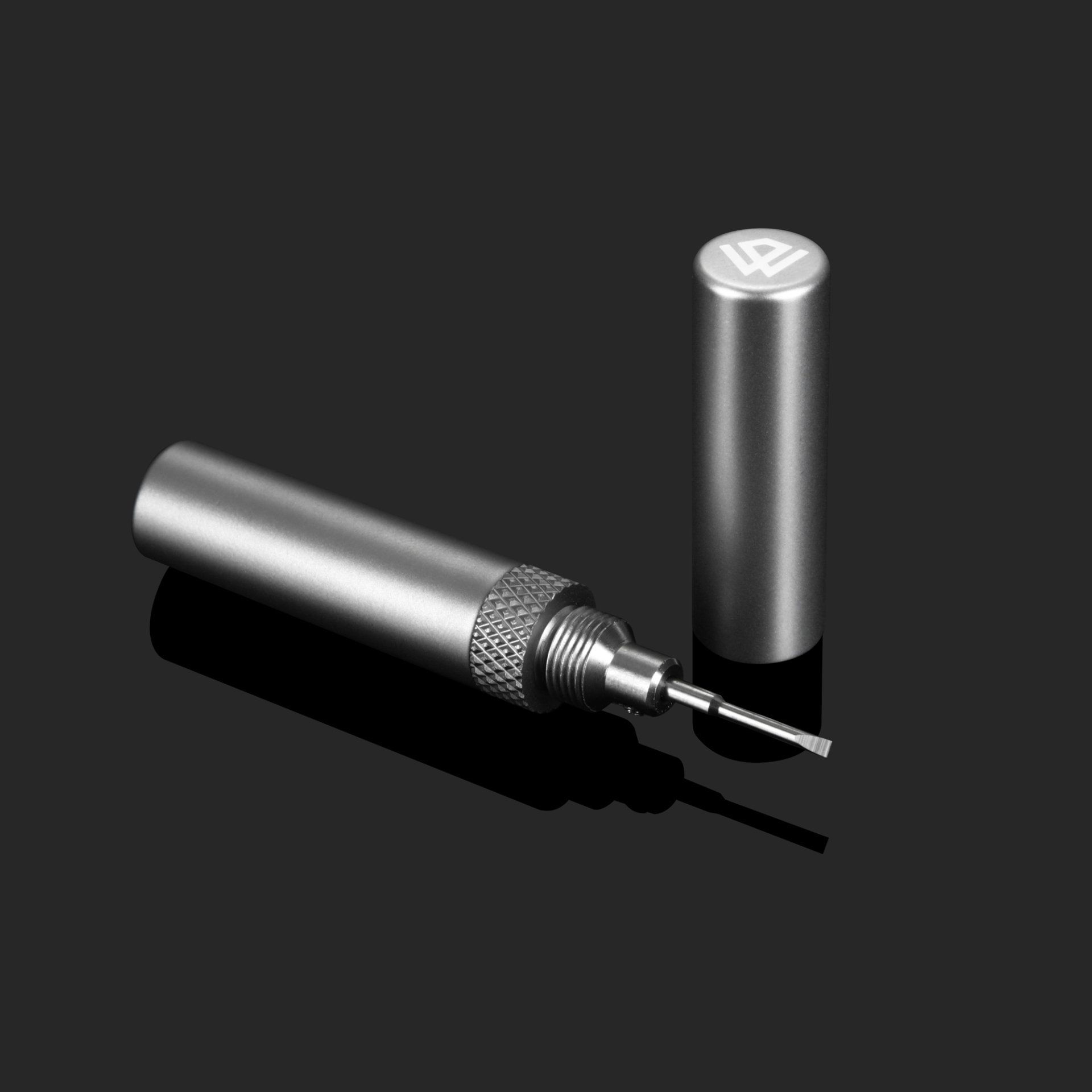 A stainless steel tool with a needle in it is sitting on a black surface.