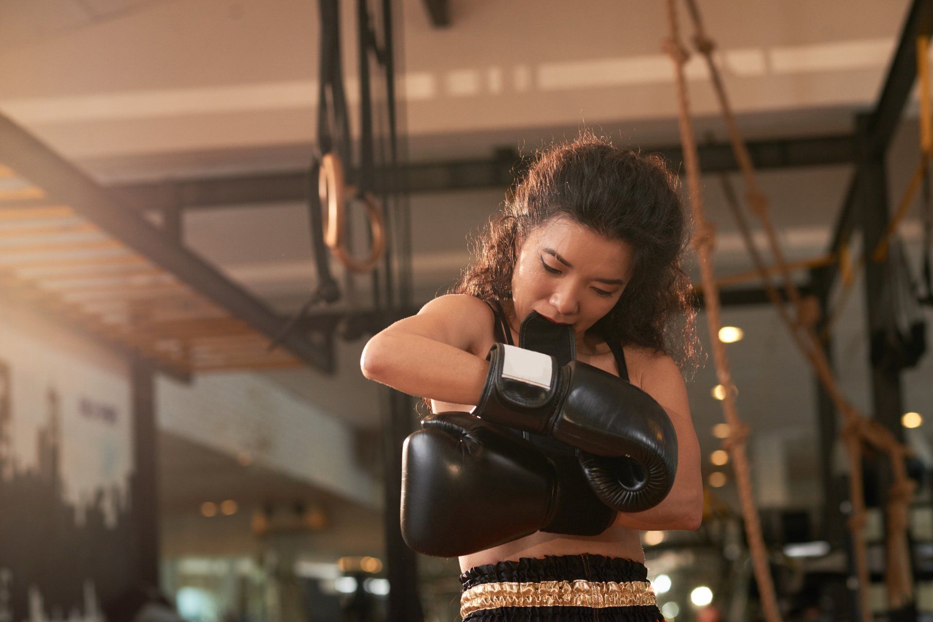 A woman is wearing boxing gloves in a gym.
