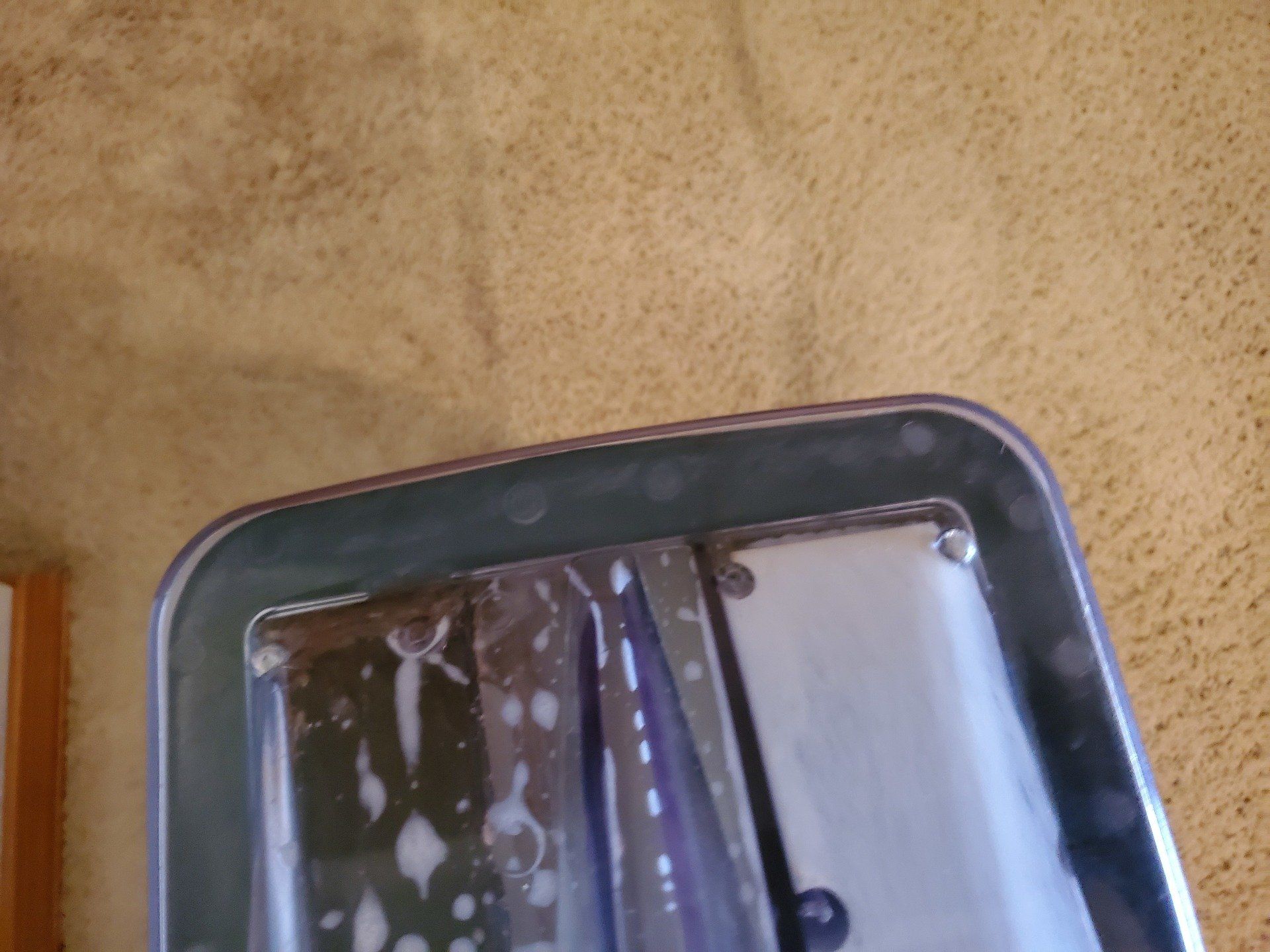 A tray with a glass in it is sitting on a wall.
