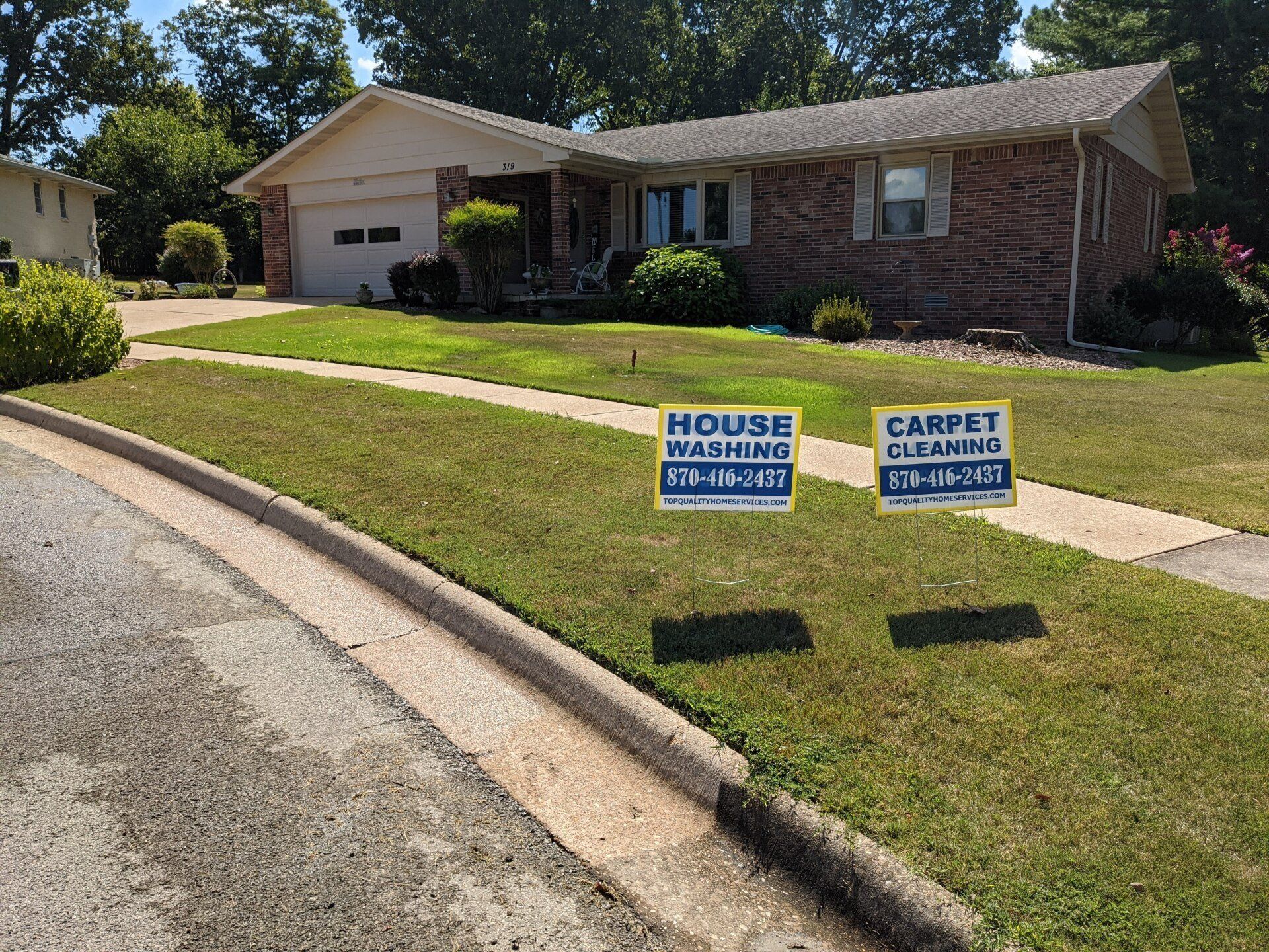 A house with two signs in front of it that say house warming and carpet cleaning