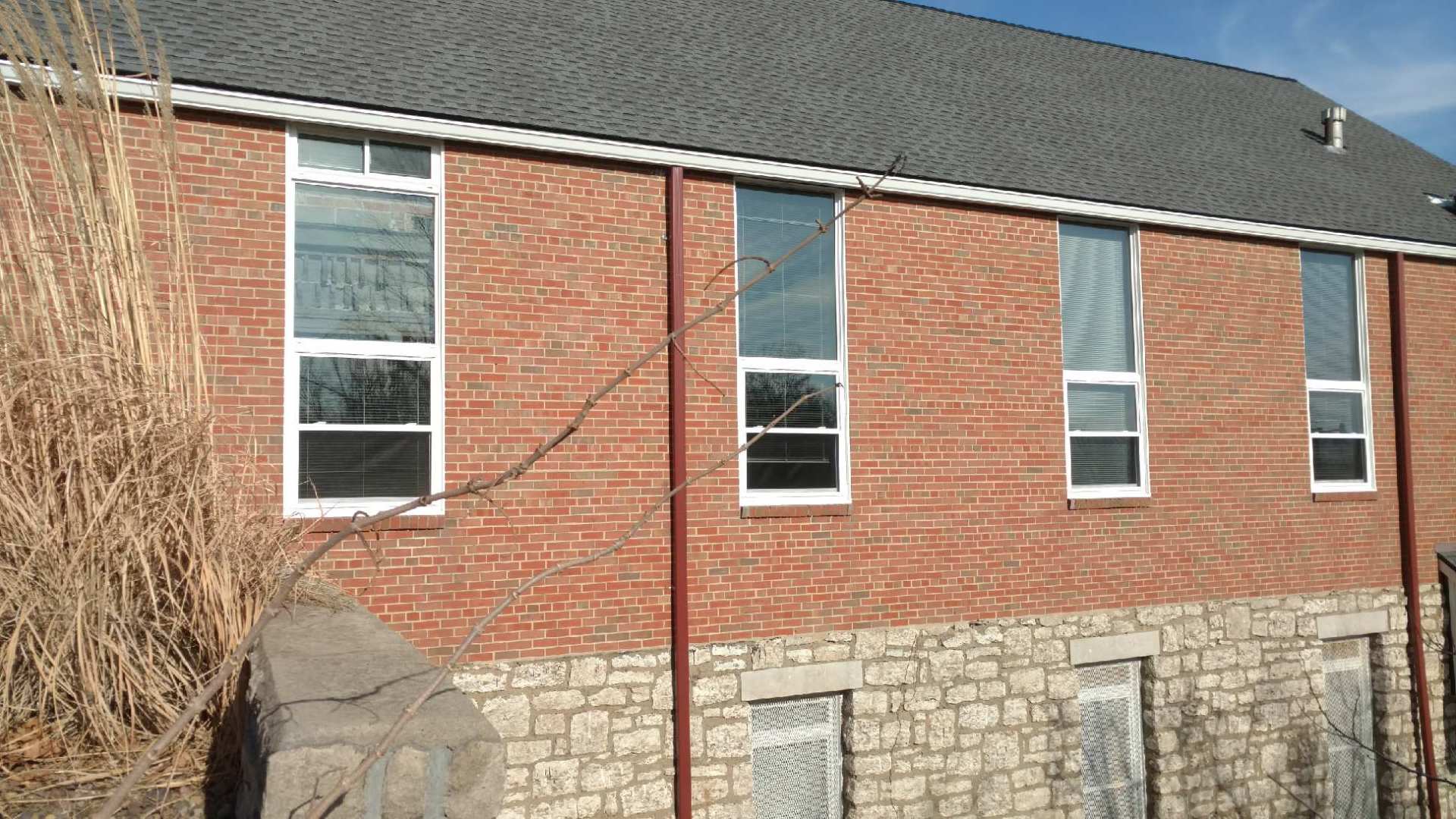 Red brick building with stone base and several tall windows under a dark roof.