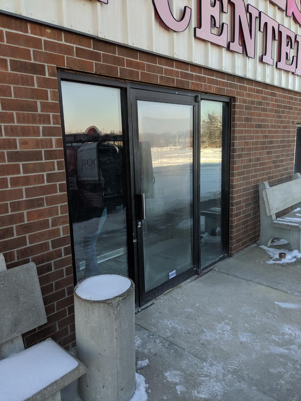 Brick storefront entrance with glass double doors and snow on the concrete outside