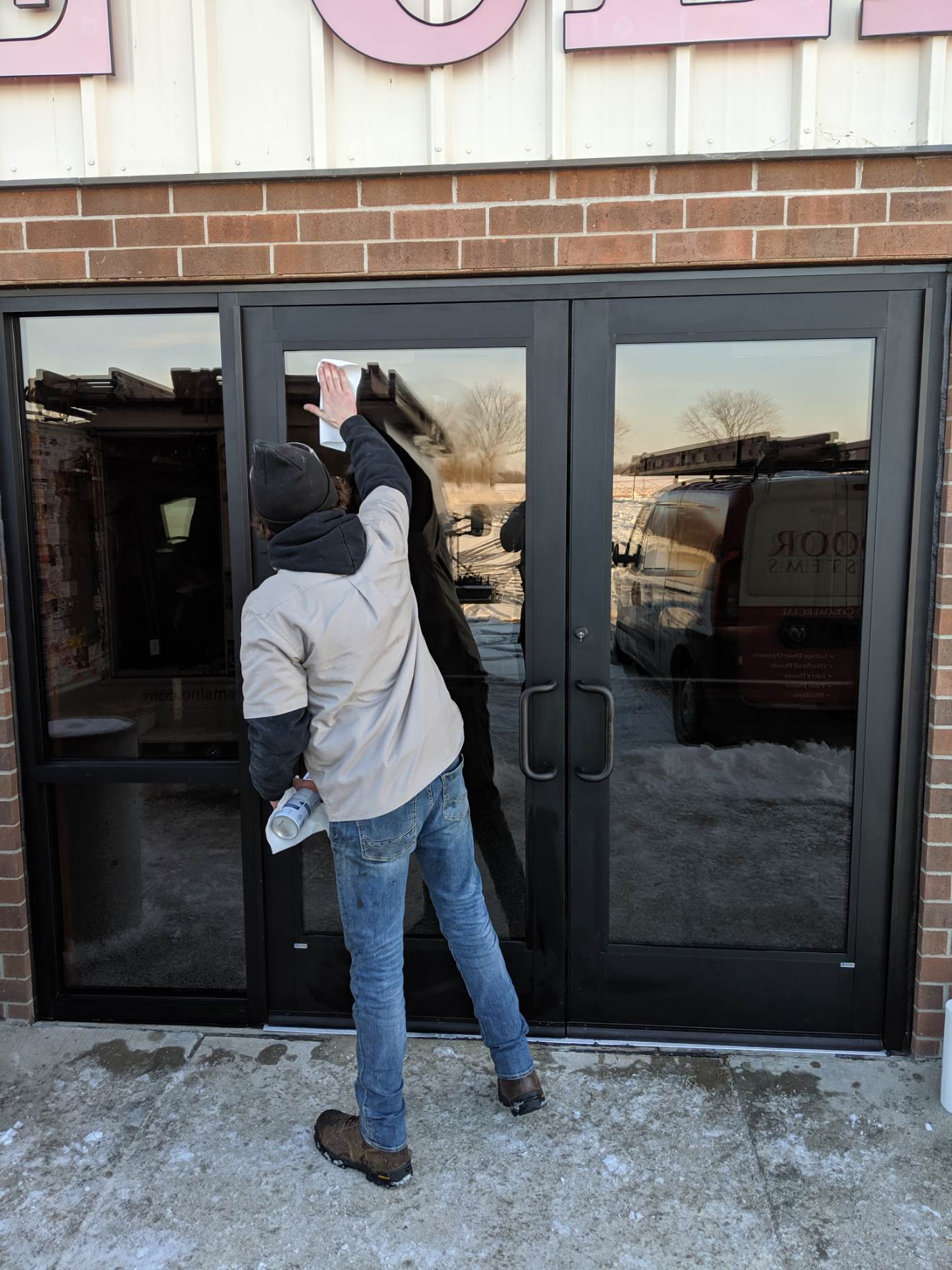 Person opening a glass storefront door in snowy weather