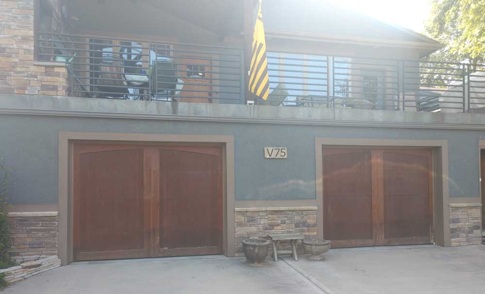 Modern two-story home facade with two wooden garage doors and a balcony above