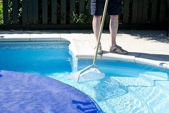 Man cleaning pool with net - Pool cleaning in Whittier, CA Man cleaning pool with net - Pool cleaning in Whittier, CA