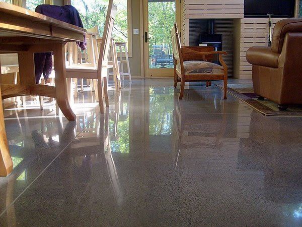 Sunlit living room with glossy tile floor, wooden chairs, and a sofa by a sliding glass door