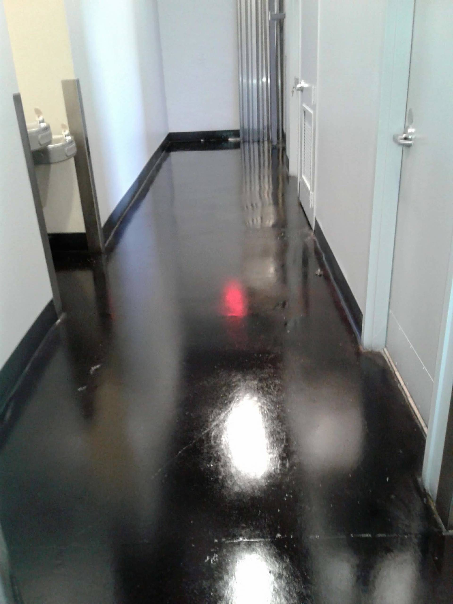 Glossy black hallway with white doors and a wall-mounted sink on the left