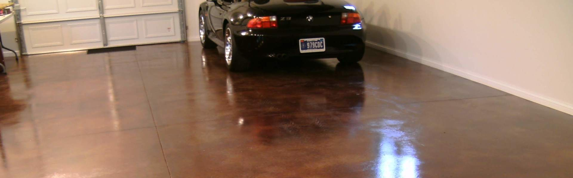 Black car parked in a glossy garage with a white door and beige walls