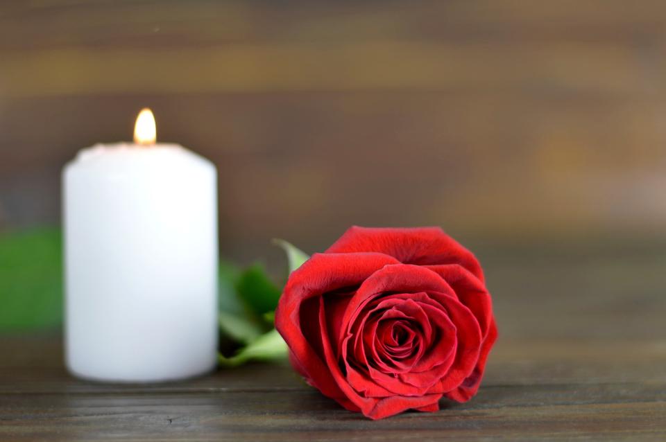 Una candela funebre e una rosa fresca