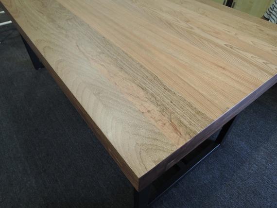 Wooden table with a light finish and dark metal legs.