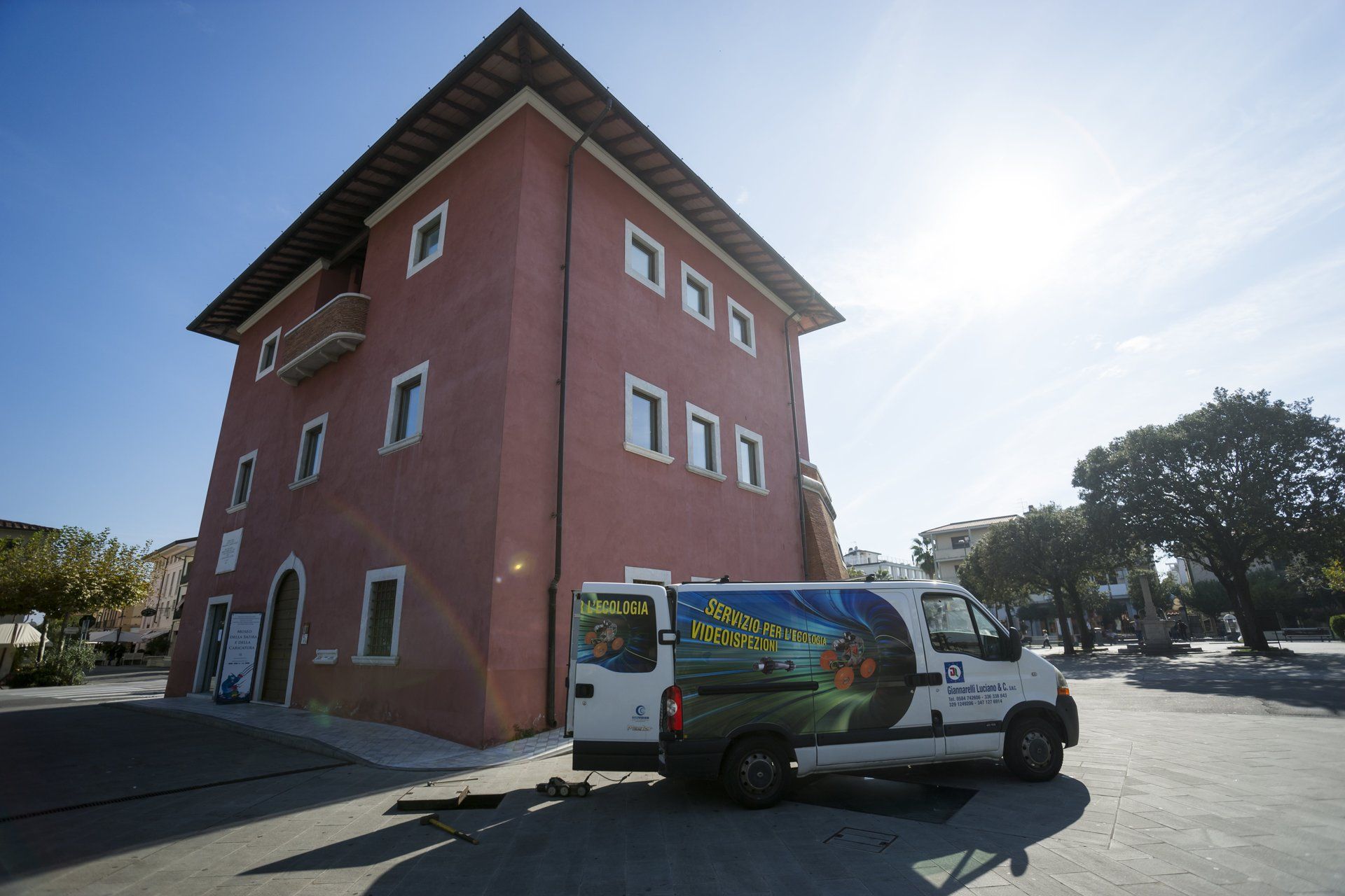 Un edificio rosso con un furgone parcheggiato per servizio di videoispezione pozzi neri.