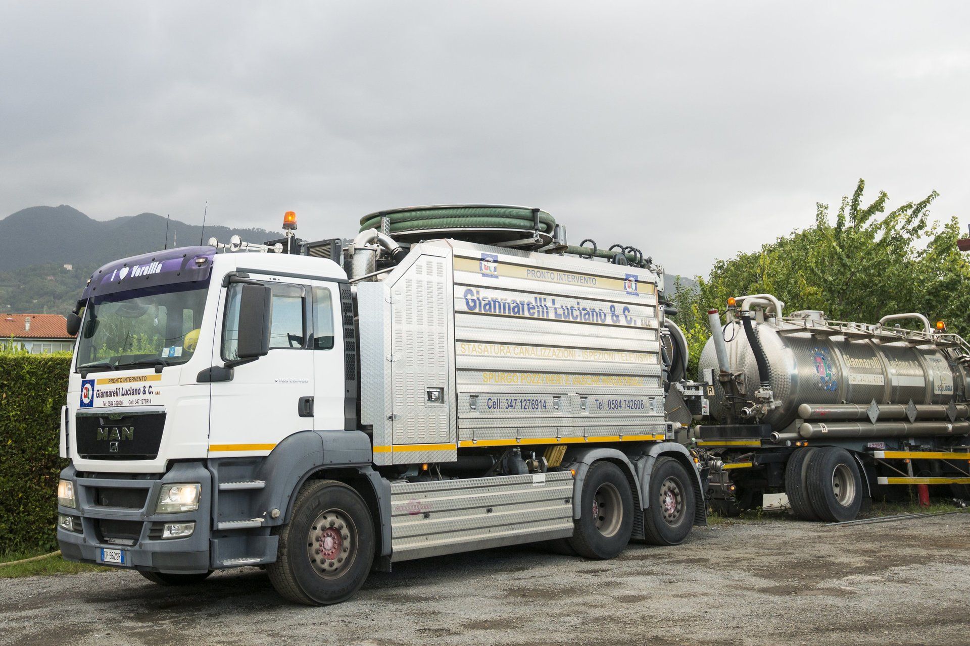 Un camion bianco con rimorchio parcheggiato fuori.