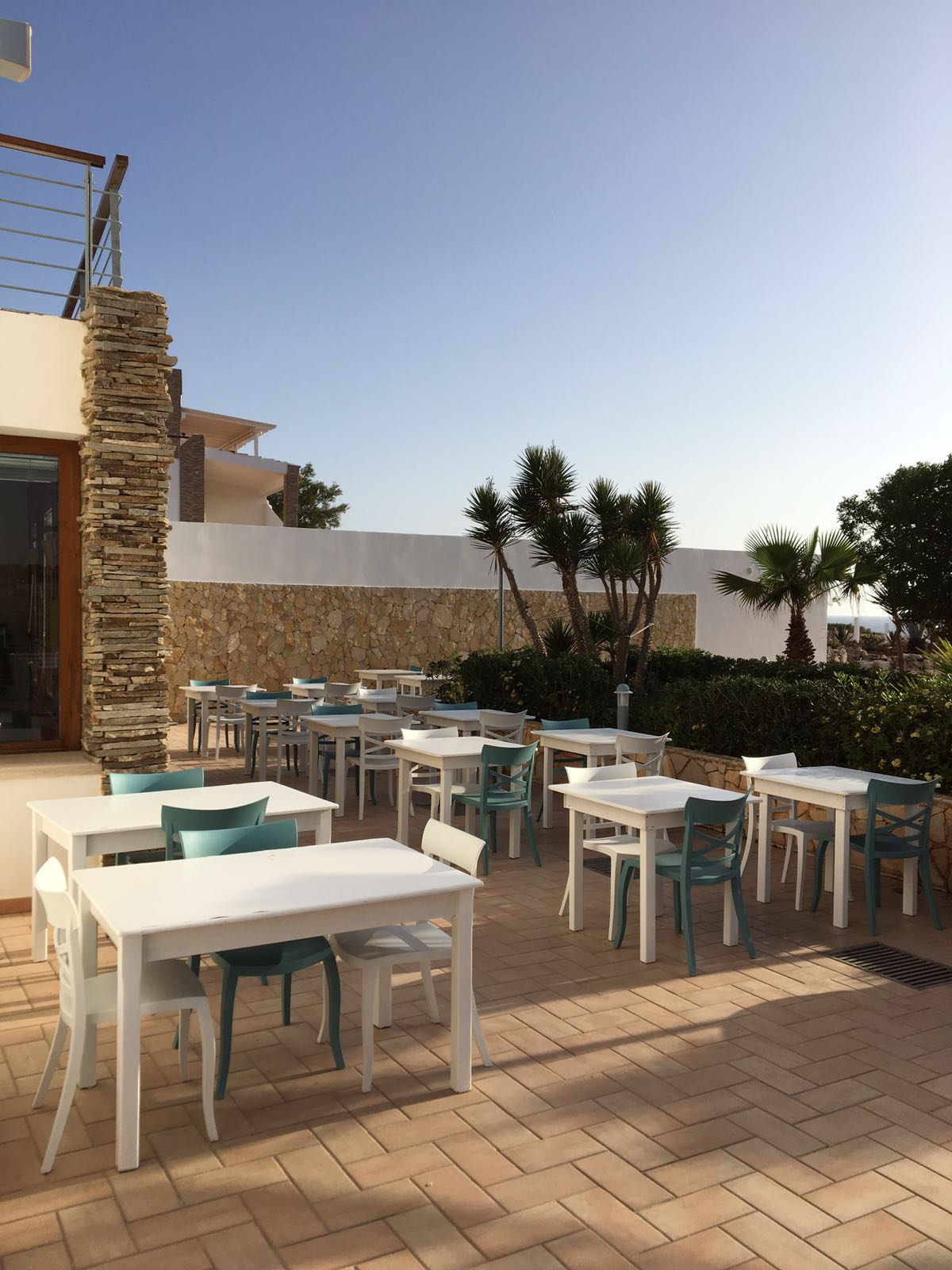 dehors di un locale con tavoli bianchi e sedie azzurre