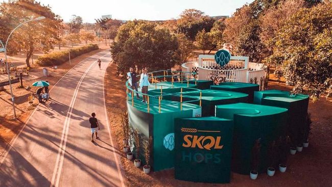 Um grupo de pessoas está caminhando por uma rua em frente a um prédio que diz skol hops.
