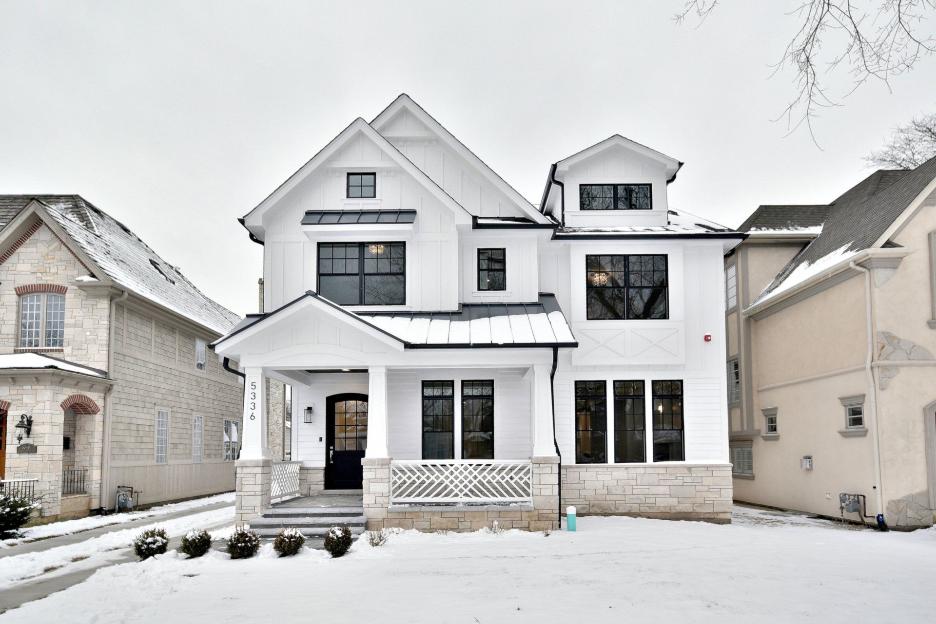 A white house is surrounded by snow covered houses