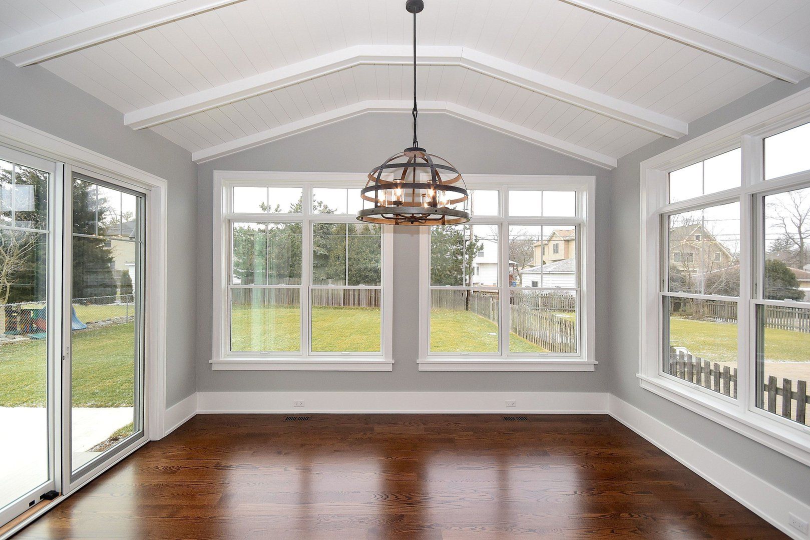 An empty room with a lot of windows and a chandelier hanging from the ceiling.