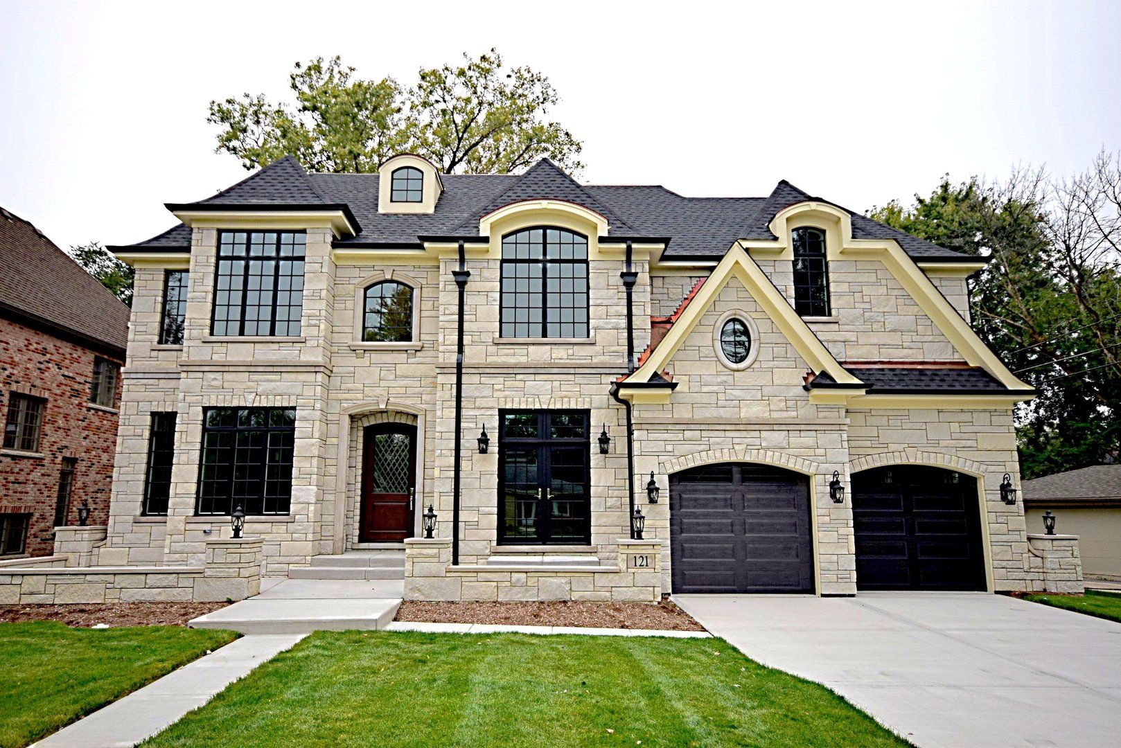 A large brick house with two garages and a lush green lawn