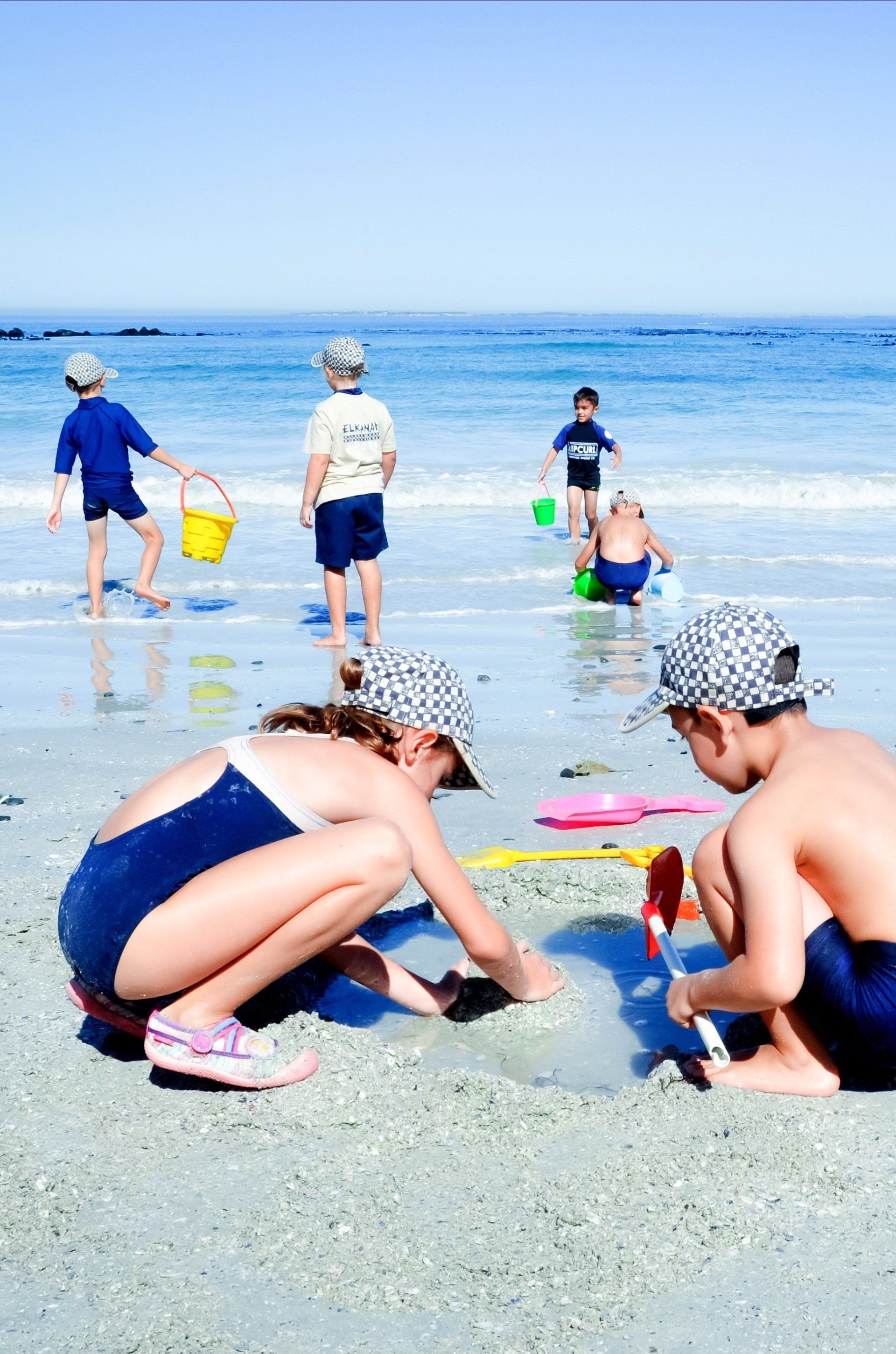 a group of children are playing in the sand on the beach