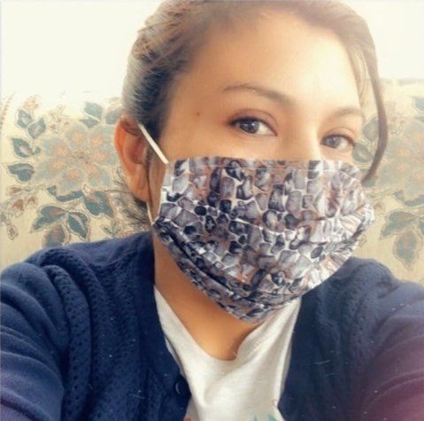 A woman wearing a face mask is sitting on a couch