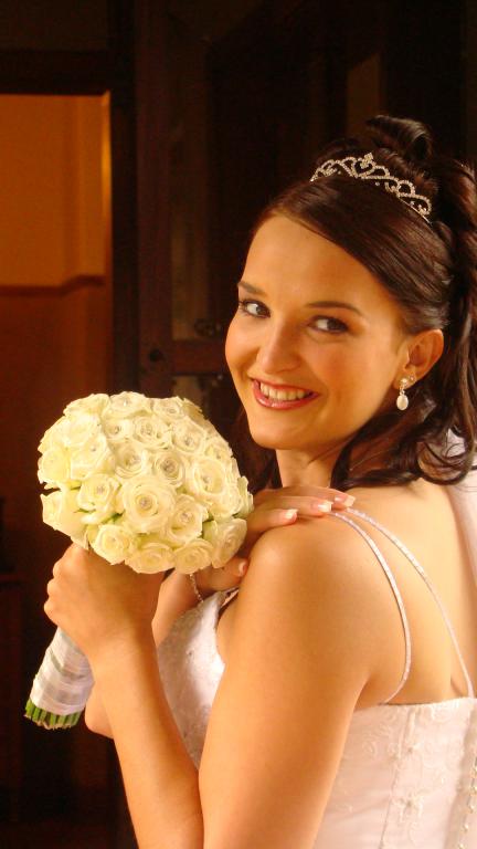 A woman in a wedding dress is holding a bouquet of white flowers.