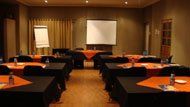 A conference room with tables and chairs and a projector screen.
