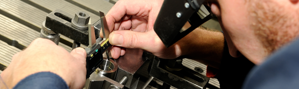 A man is working on a machine with a magnifying glass.