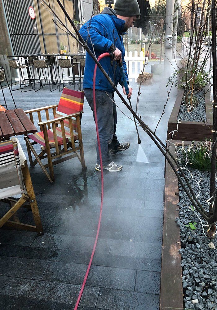 man power washing exterior stone floor