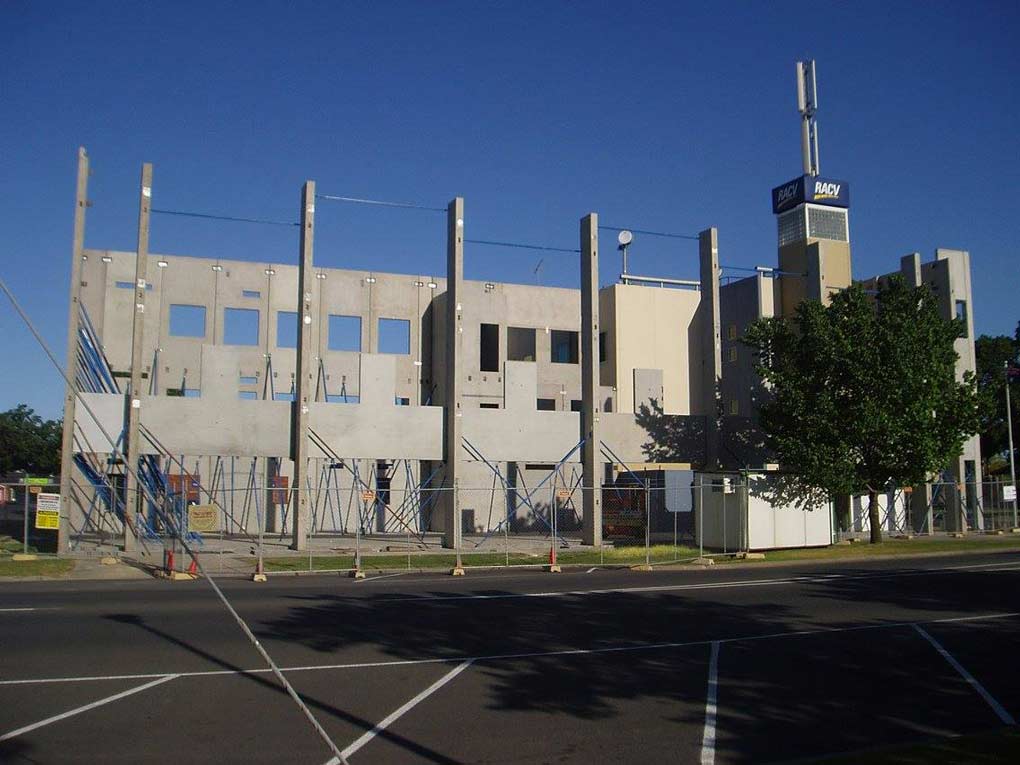 a very tall building under construction with a parking lot