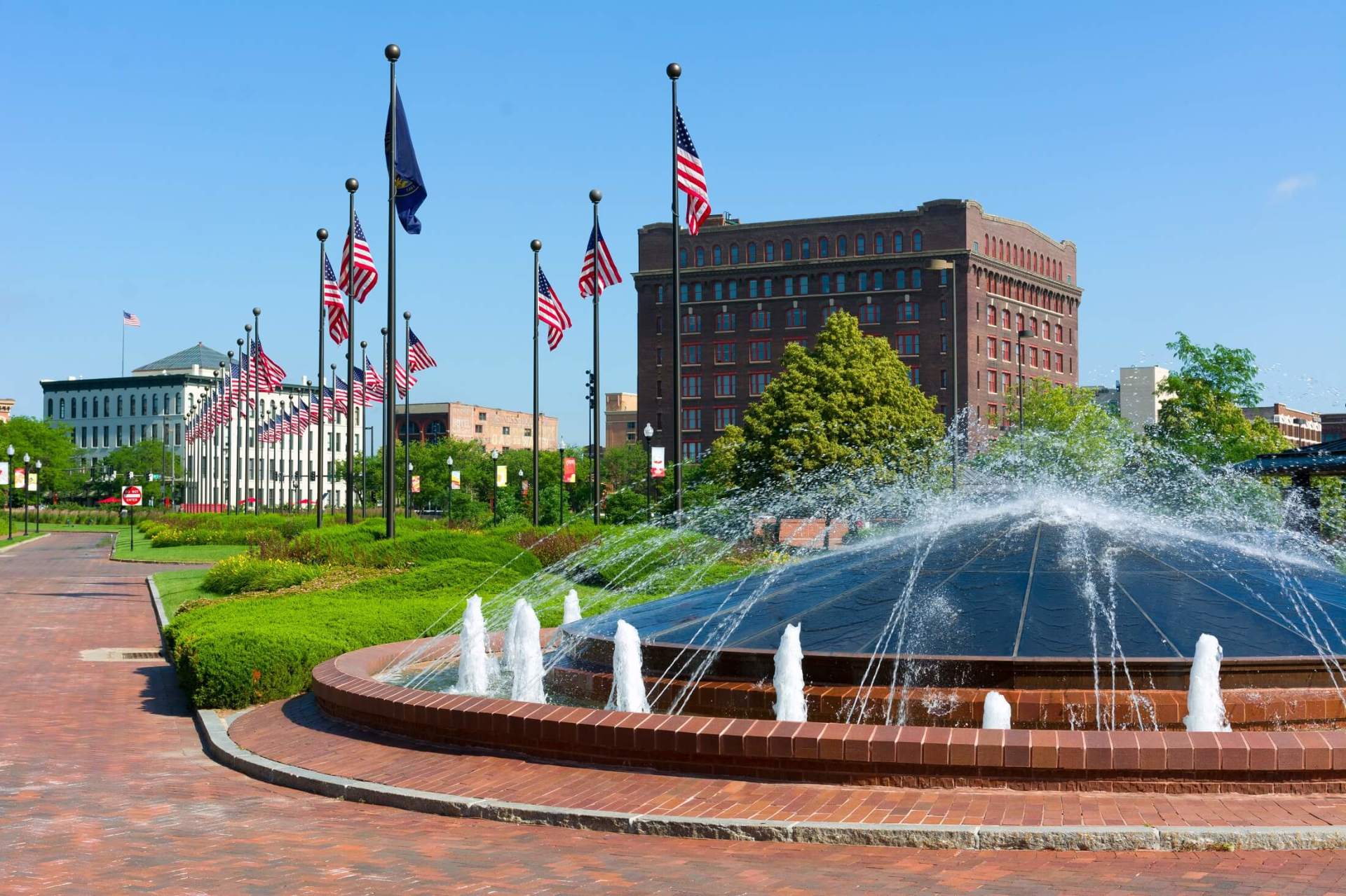 A fountain in a park with flags in the background