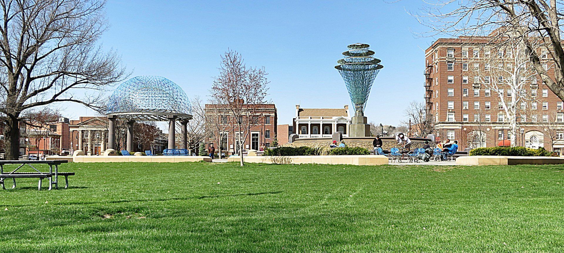 A park with a picnic table and a statue in the background