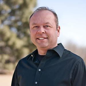 A man in a black shirt is smiling for the camera.