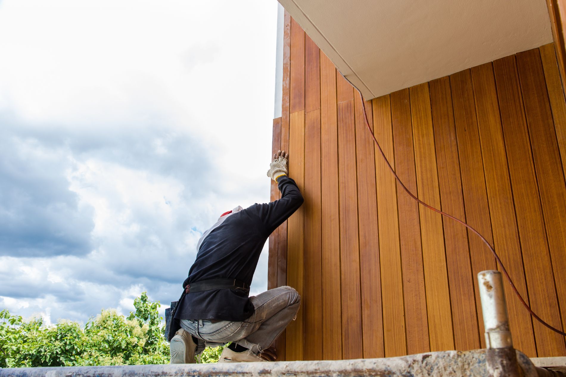 A man is painting a wooden wall of a house.