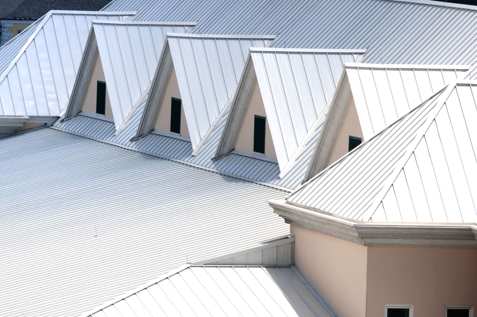 A row of white roofs on a building with black windows.