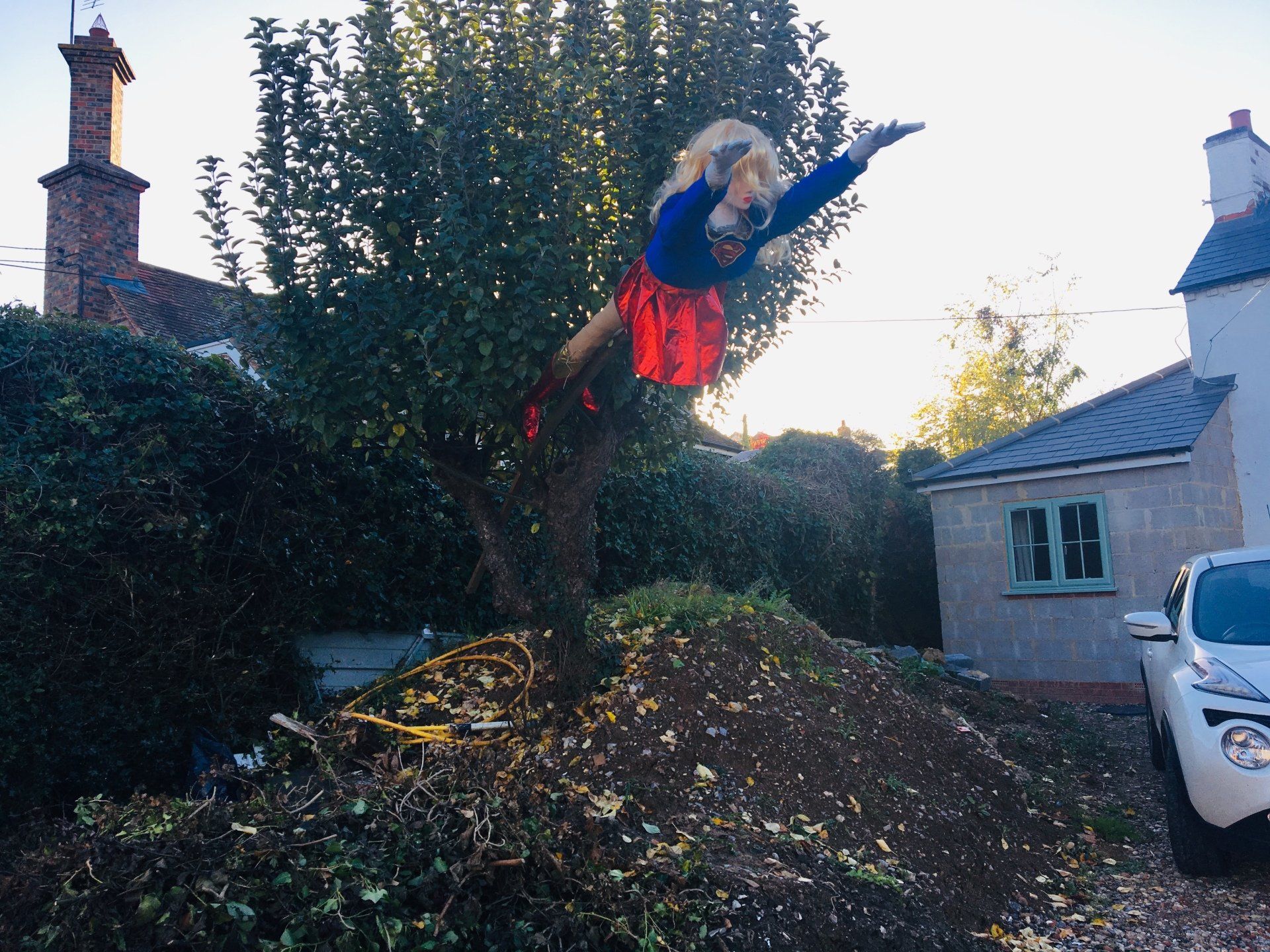 Person in Supergirl costume leaping from a pile of debris, arms outstretched.