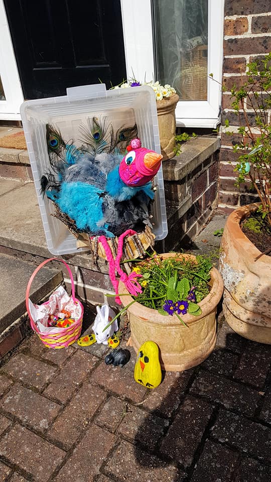 Easter decorations including a bird in a plastic box, flowerpots, a basket of candy, and small animal figures.