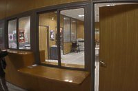 Oficina marrón con ventanas, mostradores y una puerta. Vista interior con un vistazo a la oficina tras las ventanas.