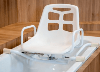 Silla de baño blanca con reposabrazos instalada sobre una bañera, en un baño con paneles de madera.