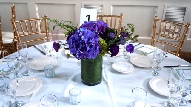 A table with a vase of purple flowers and a table number 1