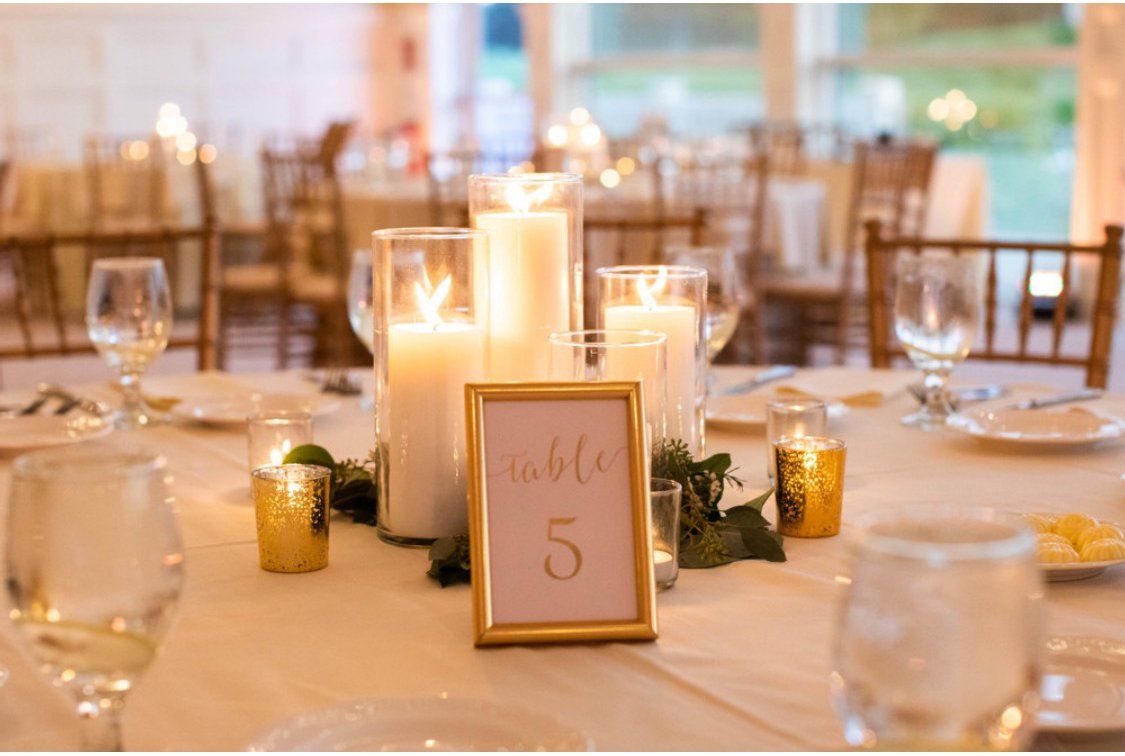 A table set for a wedding reception with candles and a table number.