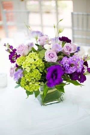A vase filled with purple and green flowers on a table.