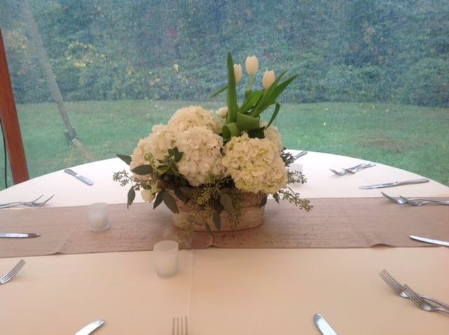 A table with a vase of white flowers on it