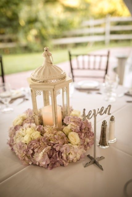 A table with a lantern , candle , and flowers on it.