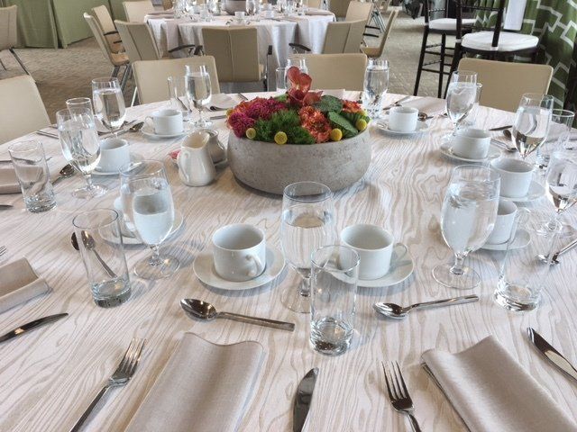 A table set for a wedding reception with a vase of flowers in the middle