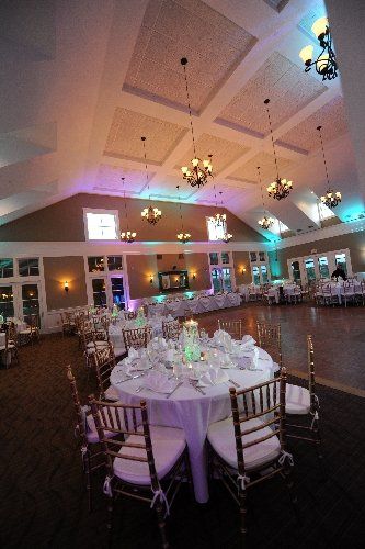 A large room with tables and chairs set up for a wedding reception