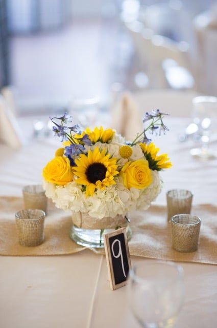 A table with a vase of yellow and white flowers and a table number 9