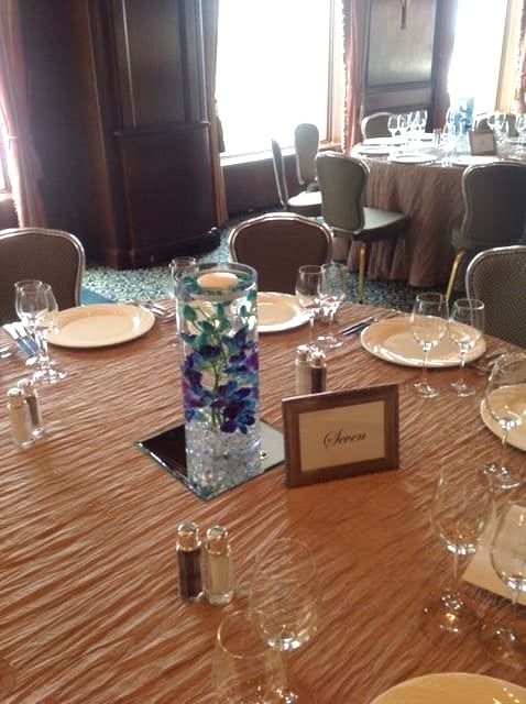 A table with plates glasses and a vase with flowers on it