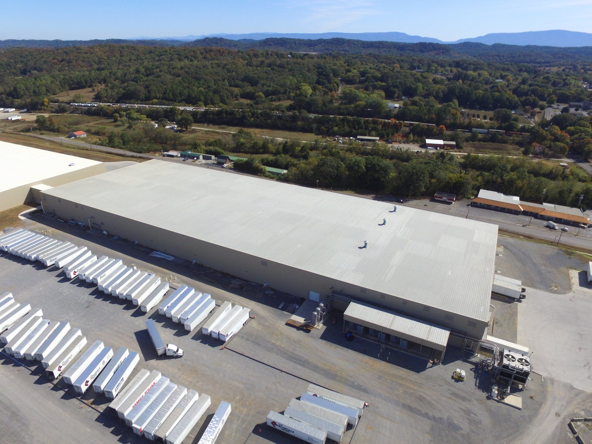 An aerial view of a large warehouse with a lot of trailers parked in front of it.