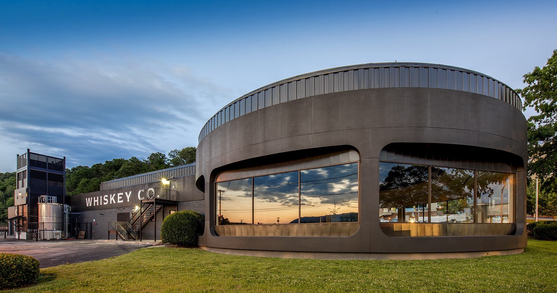 A large round building with a lot of windows is sitting on top of a lush green field.