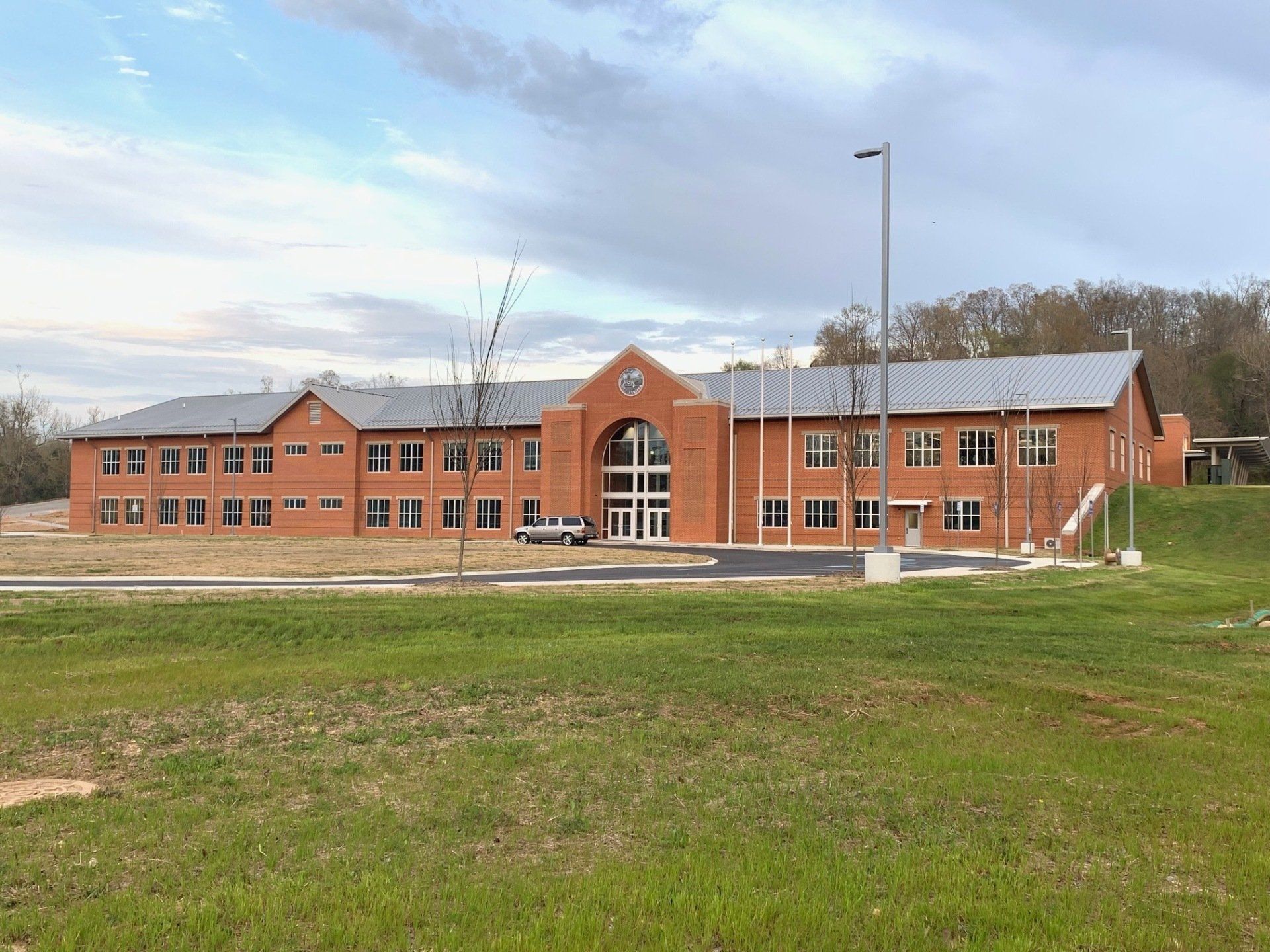 A large brick building is sitting in the middle of a grassy field.